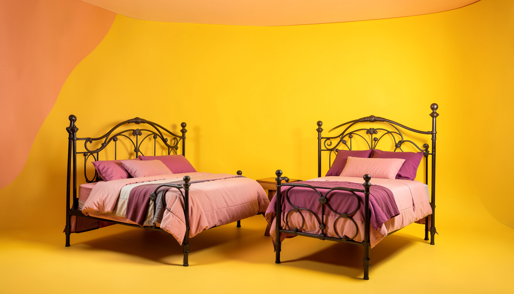 Chambre aux tons ocre rose et prune, deux lits jumeaux en fer forgé, ambiance reposante avec vue sur le parc arboré